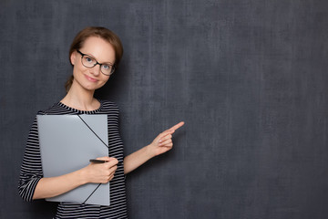 Portrait of happy cheerful girl holding folder, pointing at copy space