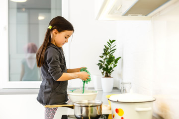 Little cute girl is cooking on kitchen. Having fun while making cakes and cookies