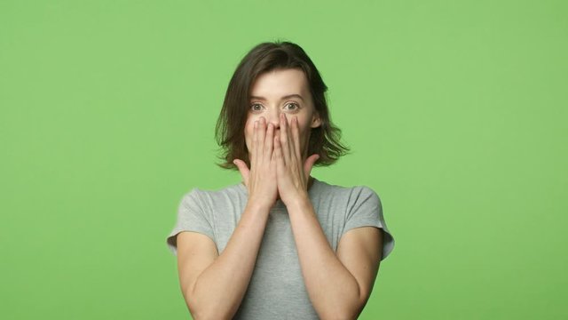 Slow-motion woman hear incredible good news. Astonished, surprised and happy smiling girl with braces, smiling cant hold cheer, congratulating friend, gesturing amused and excited, green background