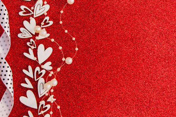 Red shiny background with a pattern of hearts, beadsand ribbon. Background for text for Valentine's Day. Free space for text.