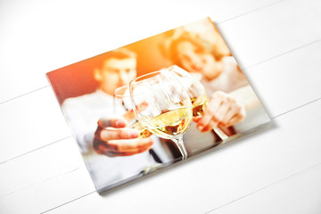 Canvas photo print on white wooden background. Sample of gallery wrapping method of canvas stretching on stretcher bar. Side view of colorful photography hanging on a wall