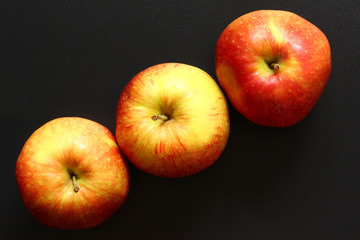 Three green red apples in a row on a black surface, copy space for text
