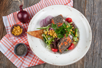 A fresh grilled salmon stake on a plate with tomatoes and salad. Grilled Salmon salad and chia seeds.