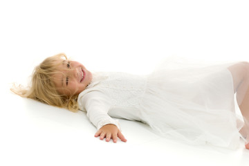 Little girl lies on the floor.Studio photo shoot on a white back