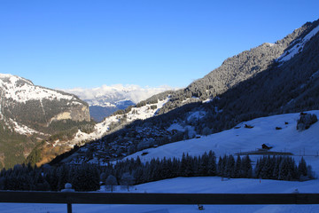 A viewpoint from atop the Swiss Alps, absorbing the mountainous landscape with snow, trees and cabins in a nearby village