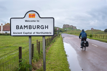 Male cyclist heading towards Bamburgh Castle, Northumberland, England