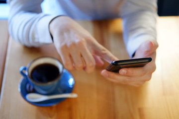 close-up of man hands using smartphone and coffee mug at background 
