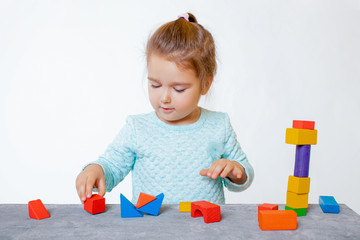 Three years old child girl playing with wooden colorful blocks and sorting shapes at home....