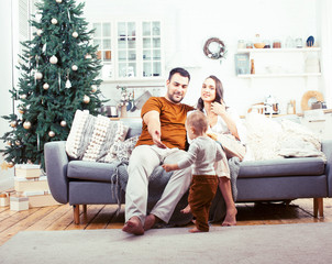 Obraz premium young happy family at home on coach waiting for Christmass with decorated tree, lifestyle people at holiday concept