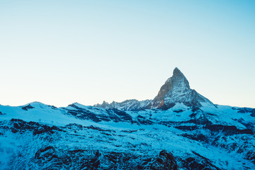 Scenic view on snowy Matterhorn mountain peak in sunny day with blue sky, Zermatt, Switzerland. Beautiful nature background of winter Swiss Alps covered with snow. Famous travel destination.