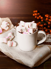 A white cup of hot chocolate with pink marshmallows. Winter drink. Winter mood.