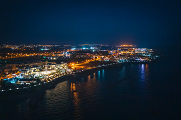 Fototapeta na wymiar Aerial panoramic view of Paphos, Cyprus seaside from above at night from drone. Beautiful evening mediterranean seascape with illuminated buildings and reflections of lights in sea water