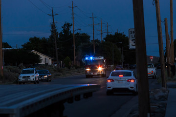 Fire truck responds to call on dark street after sunset with lights and sirens