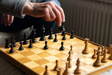 A game of chess being played, view on the board with a part of an unrecognizable man moving a piece with his hand