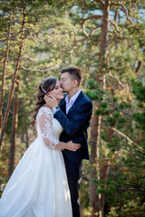 Beautiful newlyweds hugging against the backdrop of rocks and mountains. Stylish bride and beautiful bride are standing on the cliff. Wedding portrait. Family photo