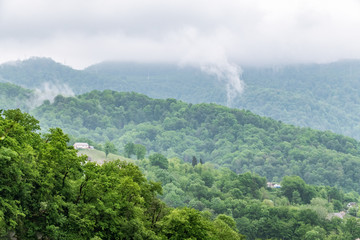 Layers of mountains in the haze in rayny day. Fog in a hilly valley with villages