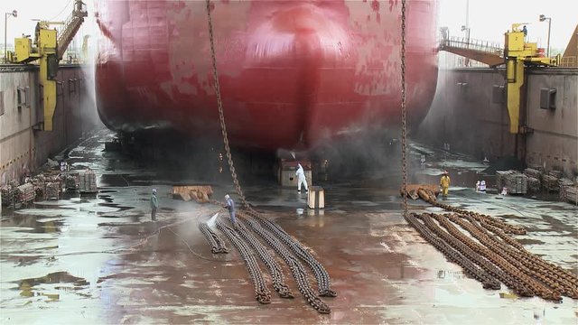 worker painting ship in the shipyard dry dock
