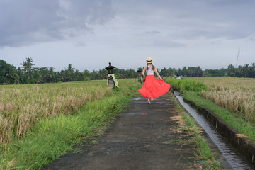 Beautiful young woman in red long maxi skirt with  straw hat and bag. Girl travel in Ubud, Bali, Indonesia