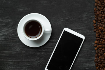 White coffee cup with white mobile phone and coffee beans on the right top view