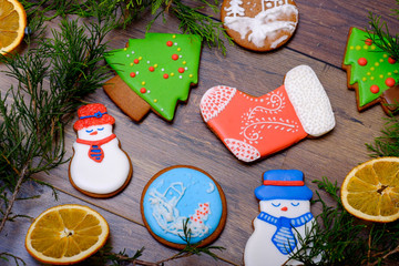 Wooden background with decorative gingerbreads, cakes and Christmas tree sweets dessert. Holidays postcard with sweet cookies food. Sugar snowman, Christmas balls and fir tree.