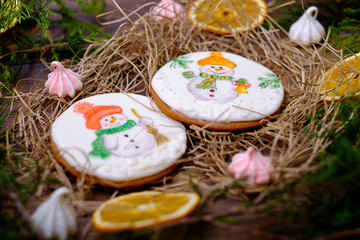 Wooden background with decorative gingerbread snowman cakes, Christmas tree branches, balls, oranges. Christmas postcard with sweets food, dessert.