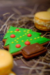 Christmas present set with sweets and oranges. Macaroons, gingerbread cookies set with snowman on wooden background. Vintage winter postcard.