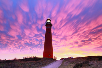 spectacular purple mammatus clouds over red lighthouse