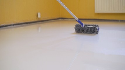 leveling the floor with a roller. The interior of the apartment is under construction....