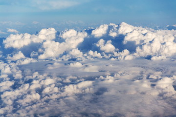Beautiful white fluffy clouds viewed from airplane, blue sky background, aerial view, copy space, travel concept