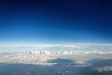 Fototapeta na wymiar Beautiful white fluffy clouds viewed from airplane, blue sky background, aerial view, copy space, travel concept