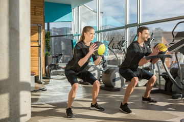 Obraz premium Man and woman doing electro muscular stimulation training in a modern gym