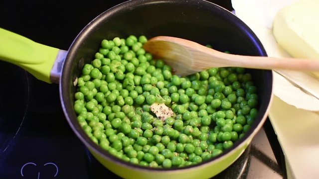 kochende Erbsen auf der Herdplatte würzen.