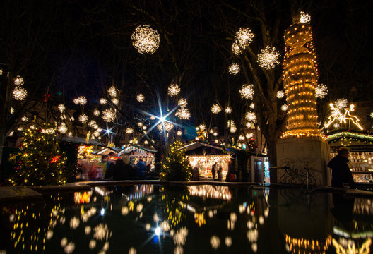Weihnachtsmarkt in Basel im Dunkeln. Die ganzen Lichter spiegeln im Brunnen