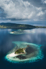 Aerial view of small tropical island with white sand beach, Beautiful clouds reflections in water surface. Tropical background.