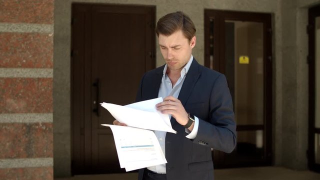 Closeup man reading business papers. Man studding business documents at street