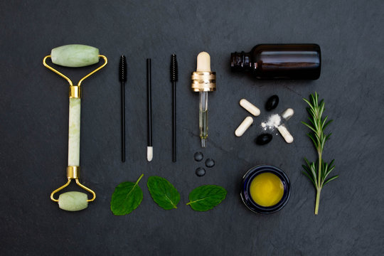 Jade Face Massage Roller And Related Healthy Green Beauty Products, Tools And Supplements Arranged In A Flat Lay Style Against A Dark Background