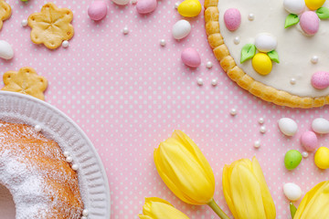 Easter background with marzipan eggs, easter cakes and spring flowers on on a pink background with...