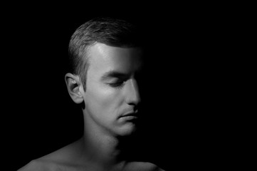 black and white dramatic portrait of a guy close-up on a black background with one light source