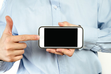 Phone in hand on a white background. A man holds a phone with a blank display in his hand. The concept of supplementing content, providing information.