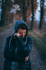 weinende, traurige Frau auf einem Feldweg mit Kaputze und Lederjacke 