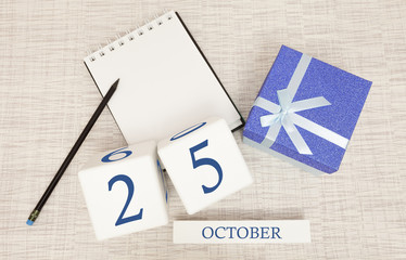 Wooden calendar for October 25, gift box in classic blue with a white ribbon, trend color numbers