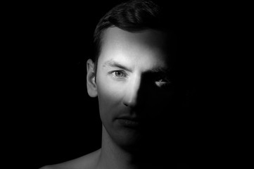 black and white dramatic portrait of a guy close-up on a black background with one light source