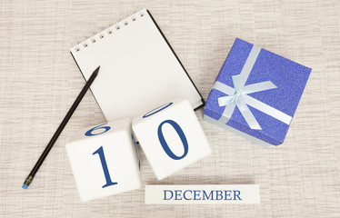 Cube calendar for December 10 and gift box, near a notebook with a pencil