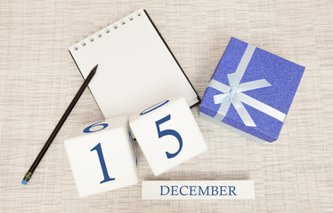 Cube calendar for December 15 and gift box, near a notebook with a pencil
