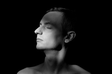 black and white dramatic portrait of a guy close-up on a black background with one light source