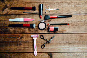 A set of cosmetics on a wooden table. The concept of doing makeup, caring for the appearance of women. Applying brushes, eye shadows, powder.