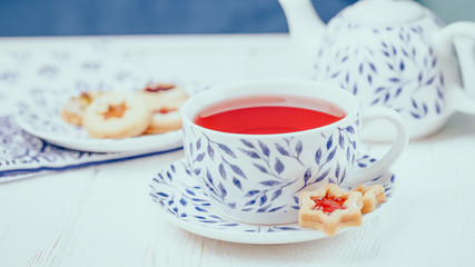 Pink fruit tea and homemade cookies stars with jam on a white wooden background, 16:9 panoramic format