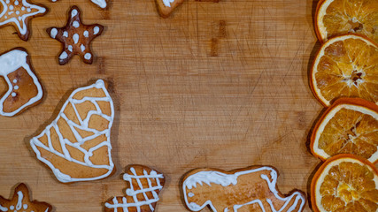 A top view of Christmas gingerbread lying on a wooden countertop. Lots of empty space.