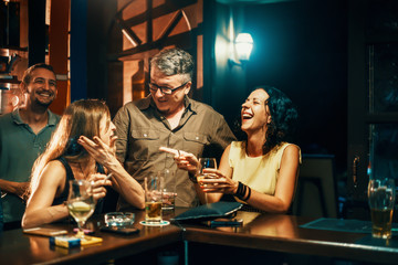 group of people drinking beer and enjoying nightlife in bar