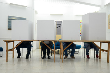 Voters on election day. Citizens casting their votes inside voting booths. Men and Women vote....